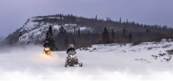 snowmobilers on a wintry forest trail