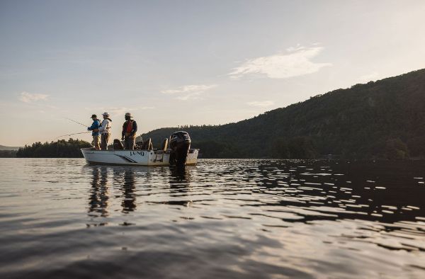 three adults fishing on a boat