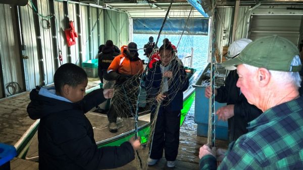 Volunteers inspect and repair nets in the cramped quarters of the spawning facility after each catch is brought in. Net repair begins in Colorado Springs at Colorado Parks and Wildlife Southeast Regional Office headquarters each December, and then each day of the spawn to keep the daily operation successful. Some volunteers have been supporting the effort for decades.