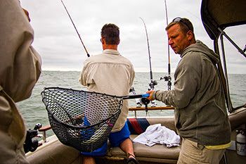 Anglers are shown fishing from a boat with a walleye in a landing net.